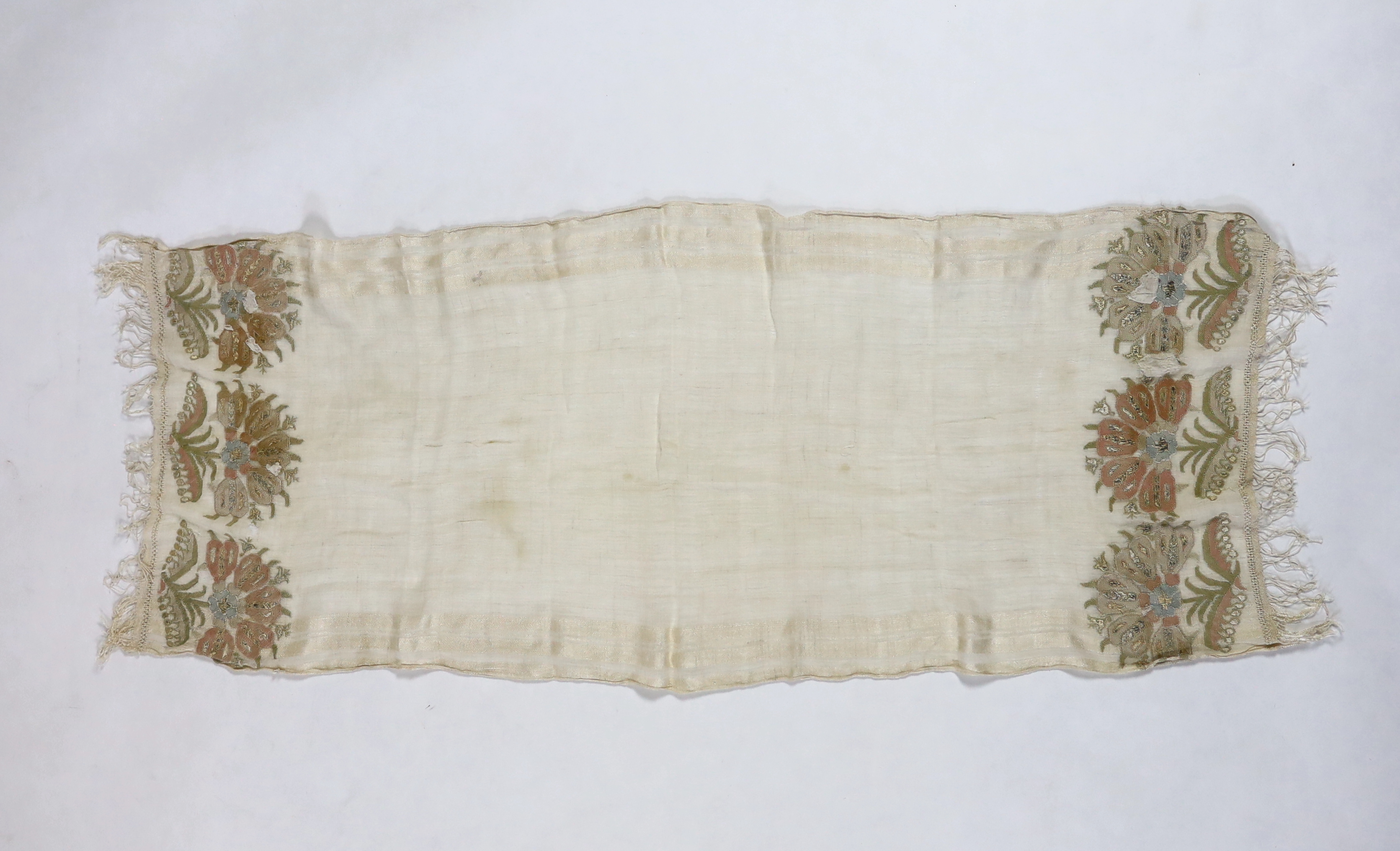 A 19th century Turkish towel, embroidered with flower motifs, in pastel shades, with fine silk fringing embroidered onto a fine hand spun linen, woven with stripes to each side, 48cm wide, 120cm long